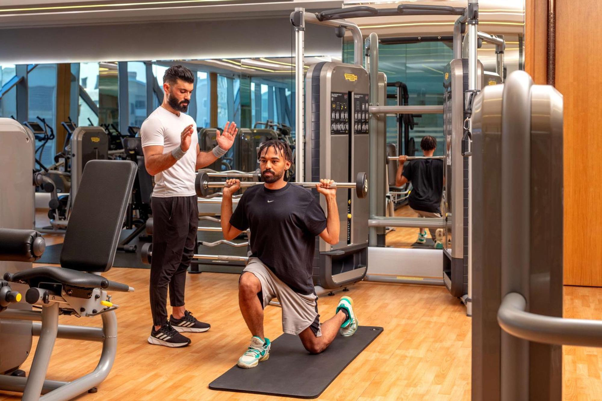 ホテル ハイアット リージェンシー リヤド オラヤ リヤード エクステリア 写真 Personal trainer coaching a man on a Bulgarian split squat